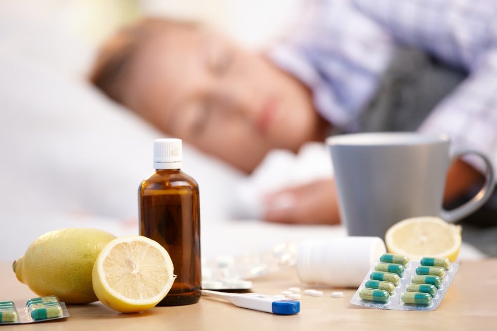 Woman Sleeping in Her Bed with Cold & Flu Remedies on Night Stand